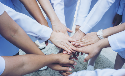 Nurses putting their hands together in a huddle